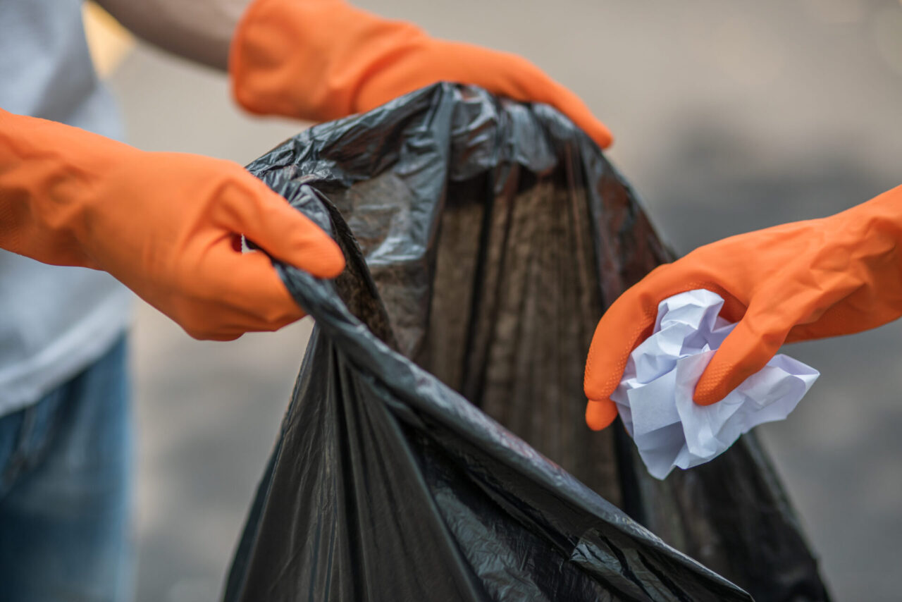 Men and women helped to collect garbage in a black bag.
